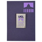 Silver pin badge with 'UCL200' logo on a purple backing card